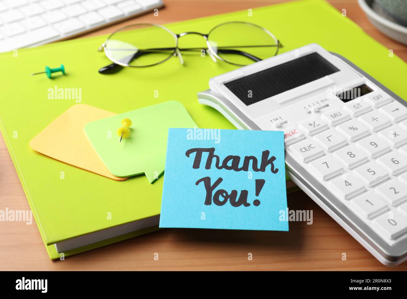 Light blue paper note with phrase Thank You, calculator and notebook on ...
