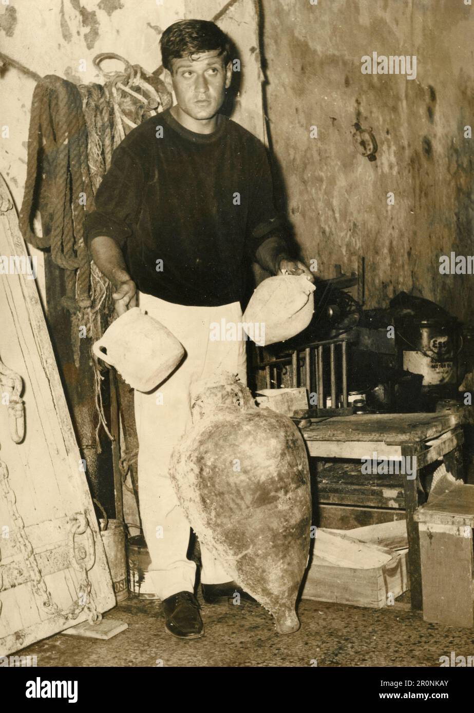 Man showing ancient pots and amphora found underwater, Italy 1965 Stock Photo