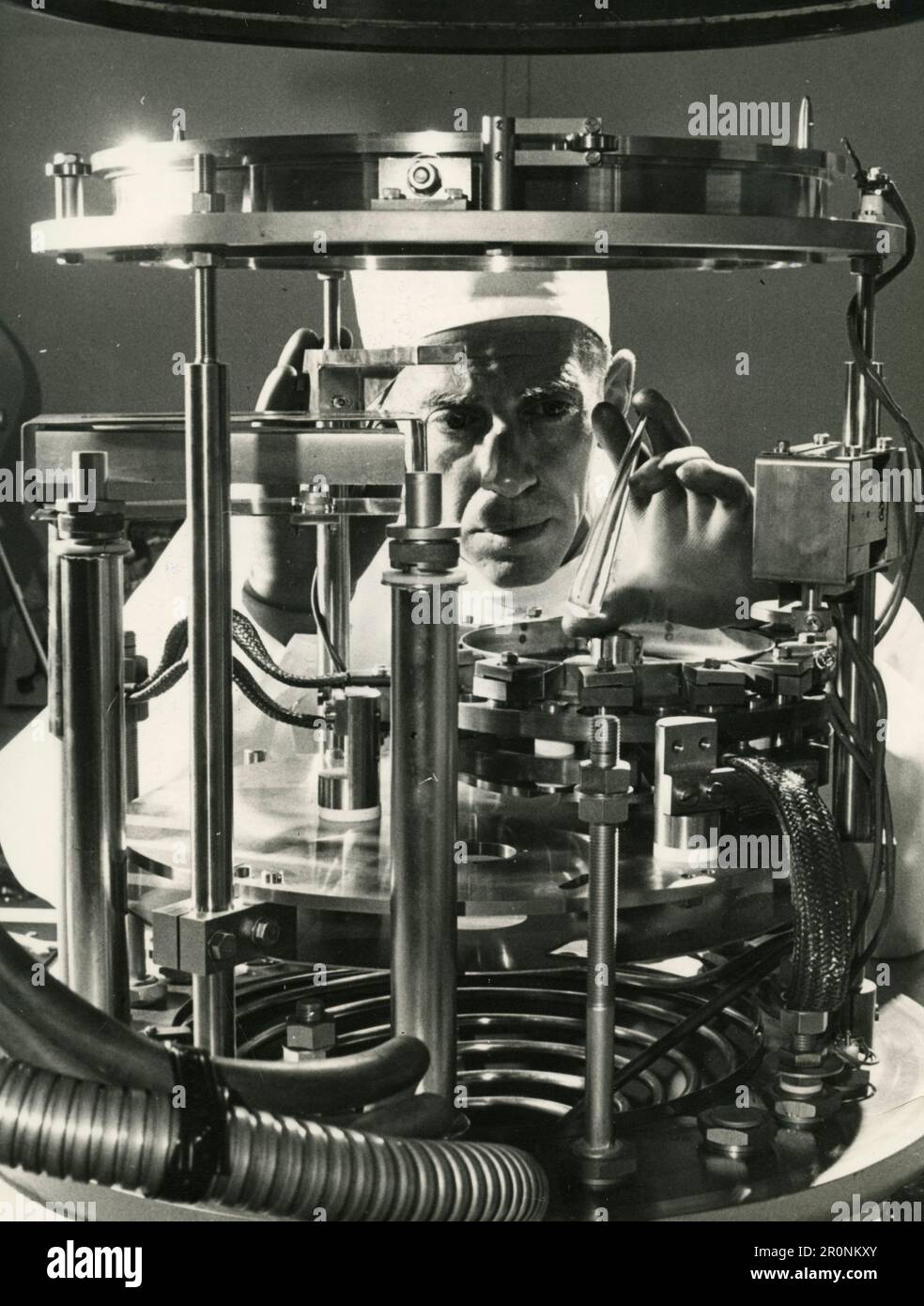 Technician at work placing a component in the vacuum chamber for coating thin film microcircuitry, UK 1966 Stock Photo