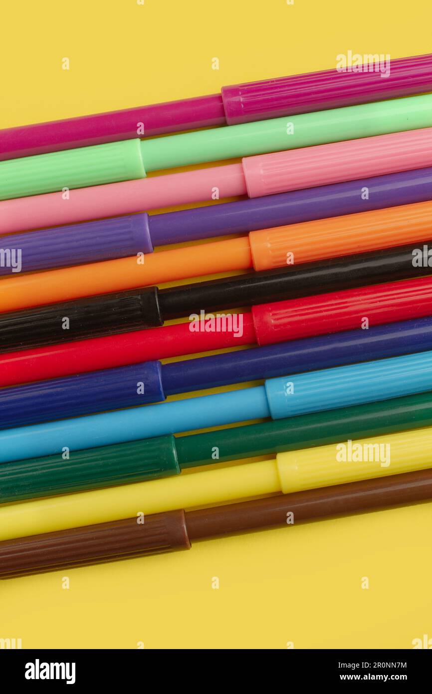 Colored markers on a yellow background in a close up view with copy space Stock Photo