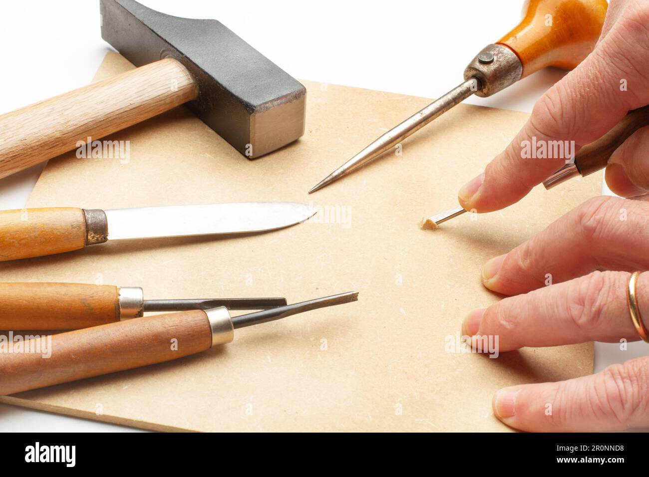 Man hand using a gouge with wooden handle on a piece of wood Stock Photo