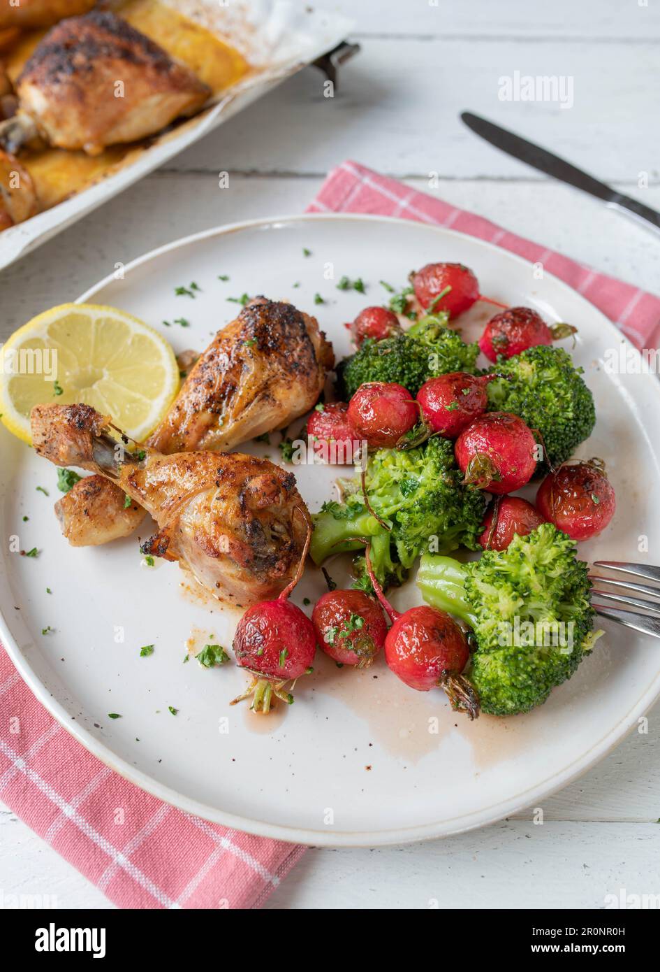 Warm salad with red radish and broccoli. Served with baked chicken on a plate Stock Photo