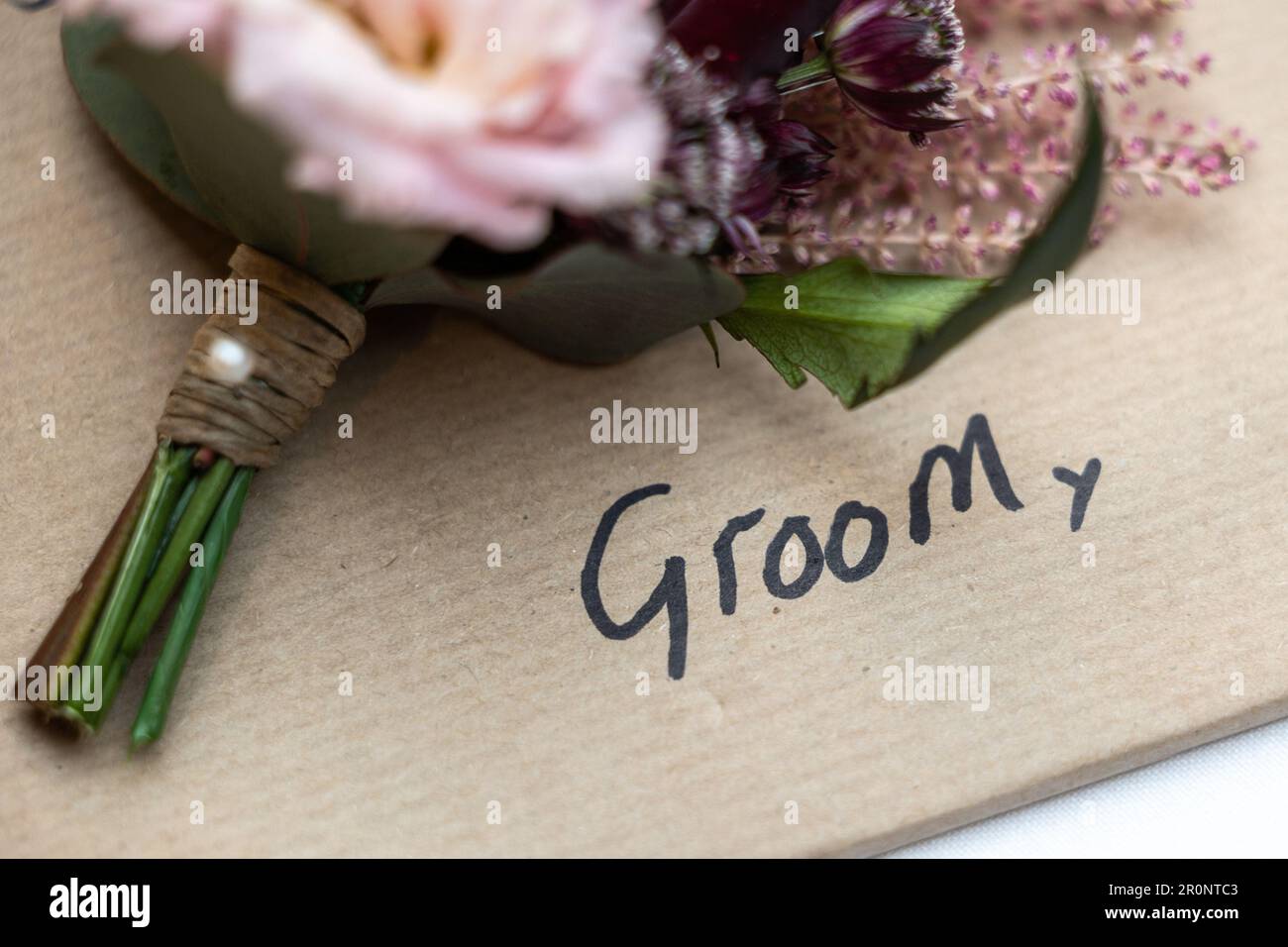Groom hand written with wedding favour flower above Stock Photo