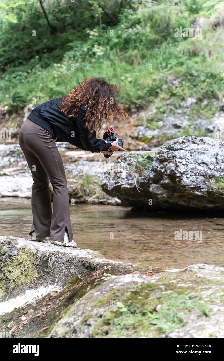 A woman stands in a picturesque landscape, capturing the beauty of a ...