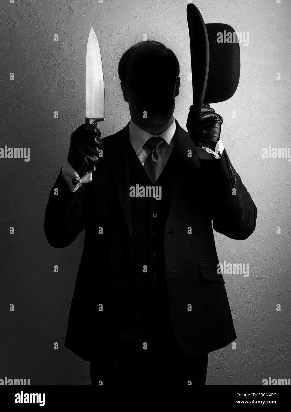 Portrait of Shadow Man in Dark Suit Holding Bowler Hat and Sharp Knife. Concept of Horror Killer Stock Photo