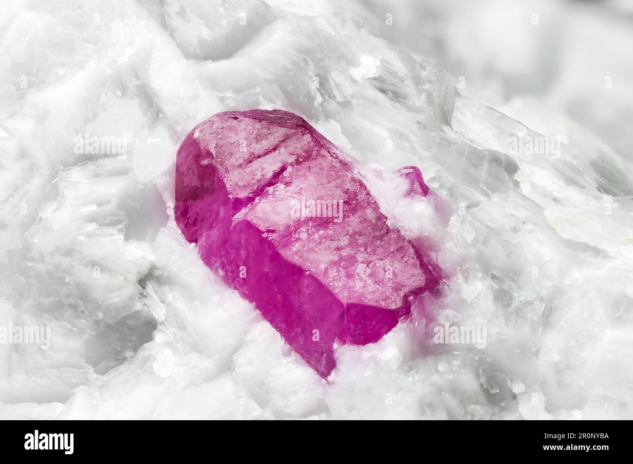 ruby crystal (red corundum) on white calcite. macro detail texture background. close-up raw rough unpolished semi-precious gemstone Stock Photo