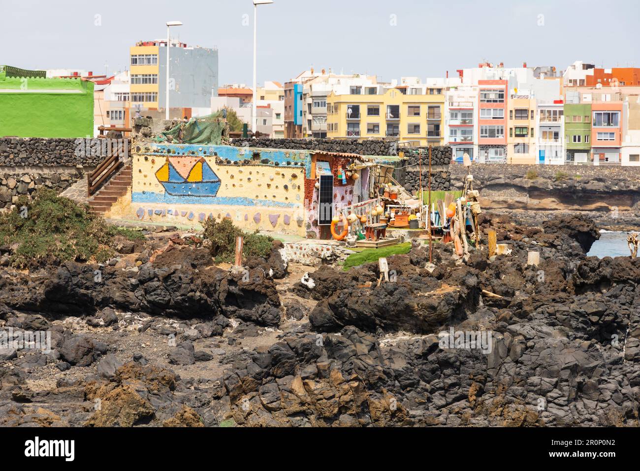 Beach shack on the rocks at Mirador El Bufadero with La Garita buildings behind. Las Palmas, Gran Canaria, Spain Stock Photo