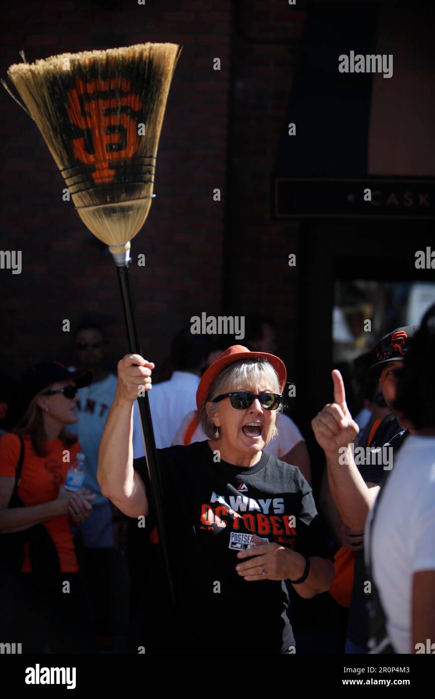Lisa Lewis of Santa Clara waves a broom with SF on it that her son made in  2011 as she stands outside of AT&T Park before Game 3 of the NLDS with