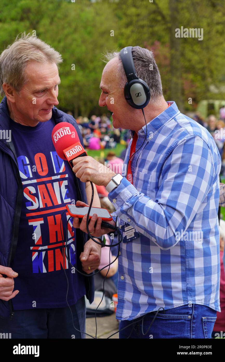 Harrogate Hospital radio outdoor reporter interviews a man wearing a 'God Save the King' t-shirt at a King Charles III Coronation event, England, UK, Stock Photo