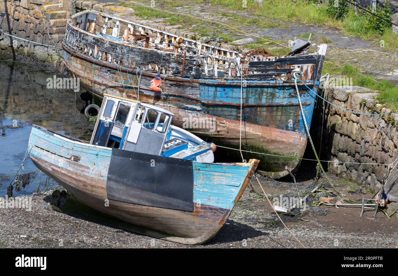 Rotting decaying wooden fishing boats alongside The Old Quay, Newlyn, Penzance, Cornwall, England, UK. Stock Photo