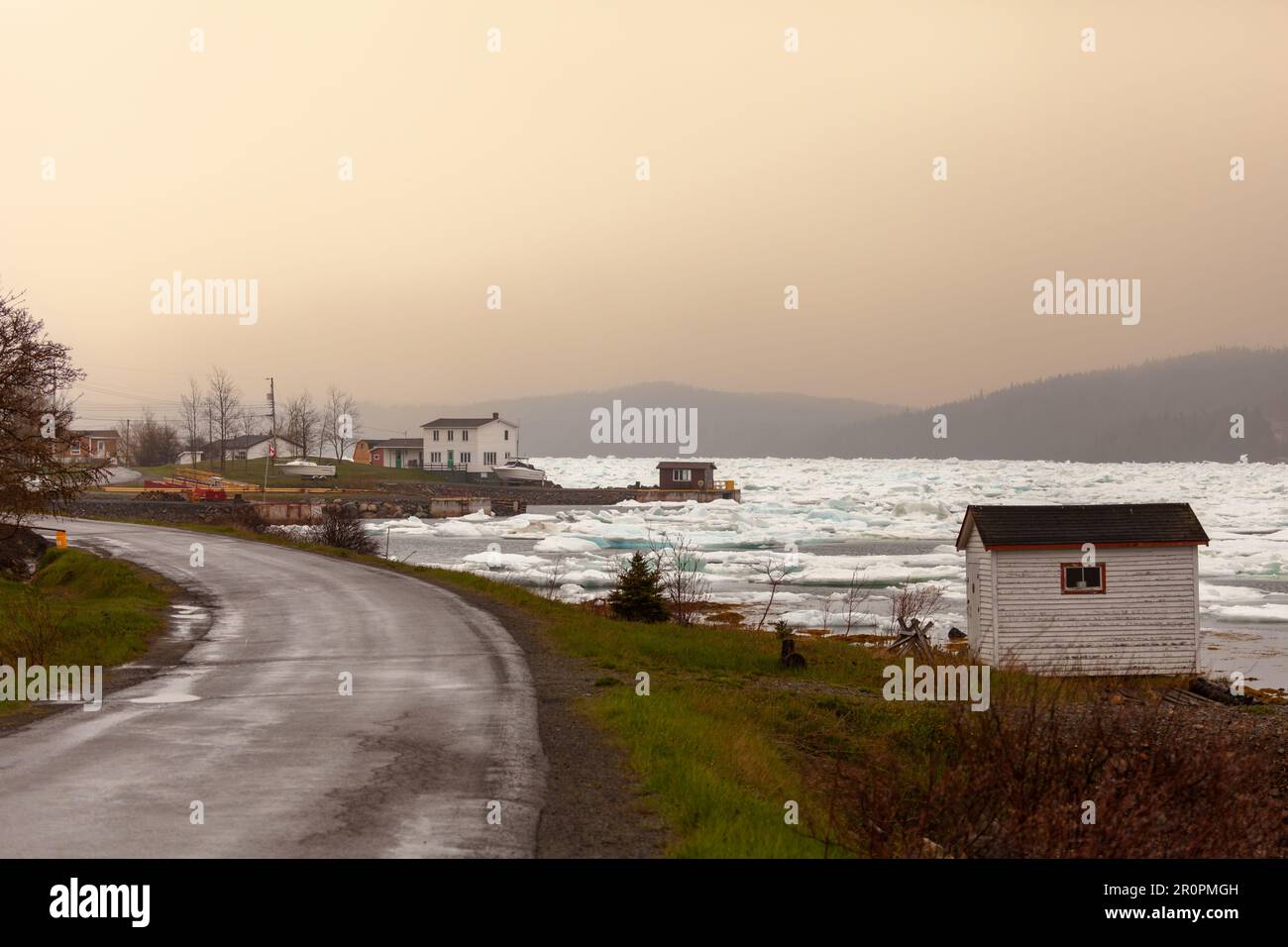 An outport village overlooks an ice-clogged inlet along a road in northern Newfoundland,. Canada Stock Photo