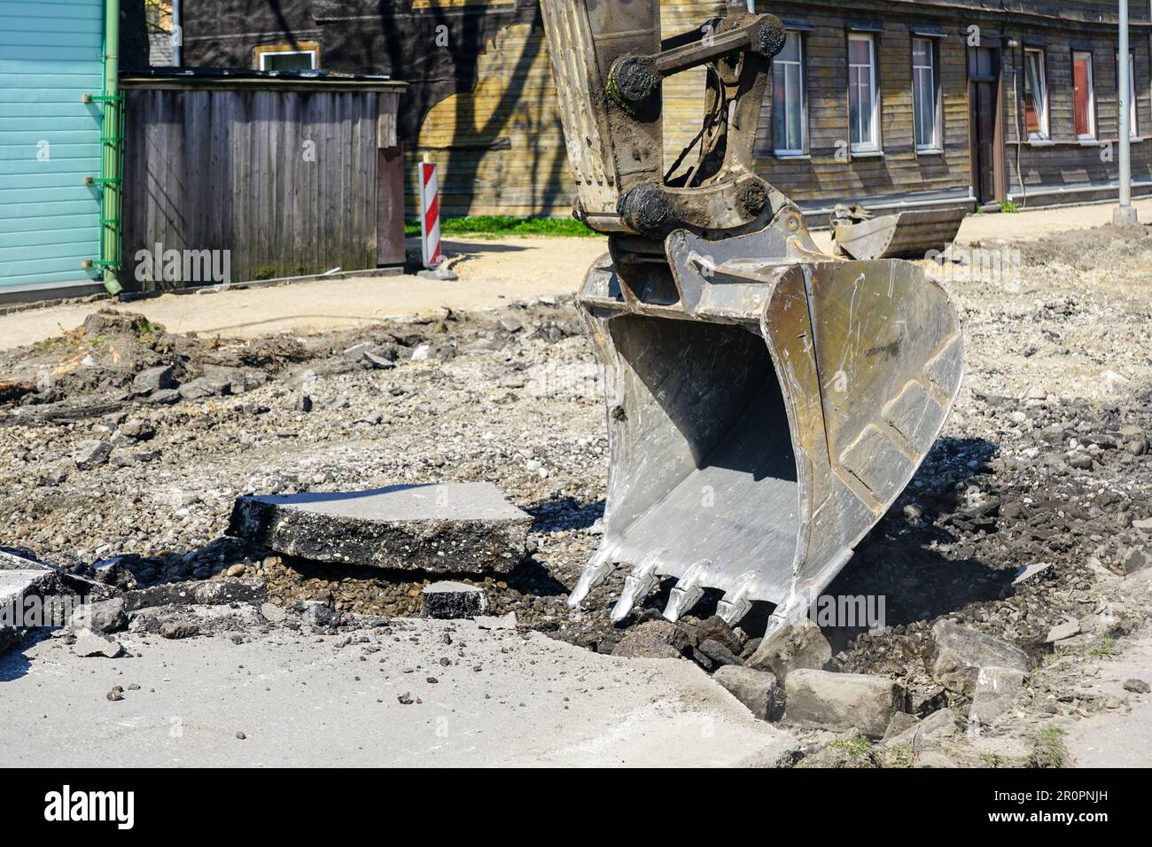 Closeup of a hydraulic excavator bucket breaking up the asphalt layer ...