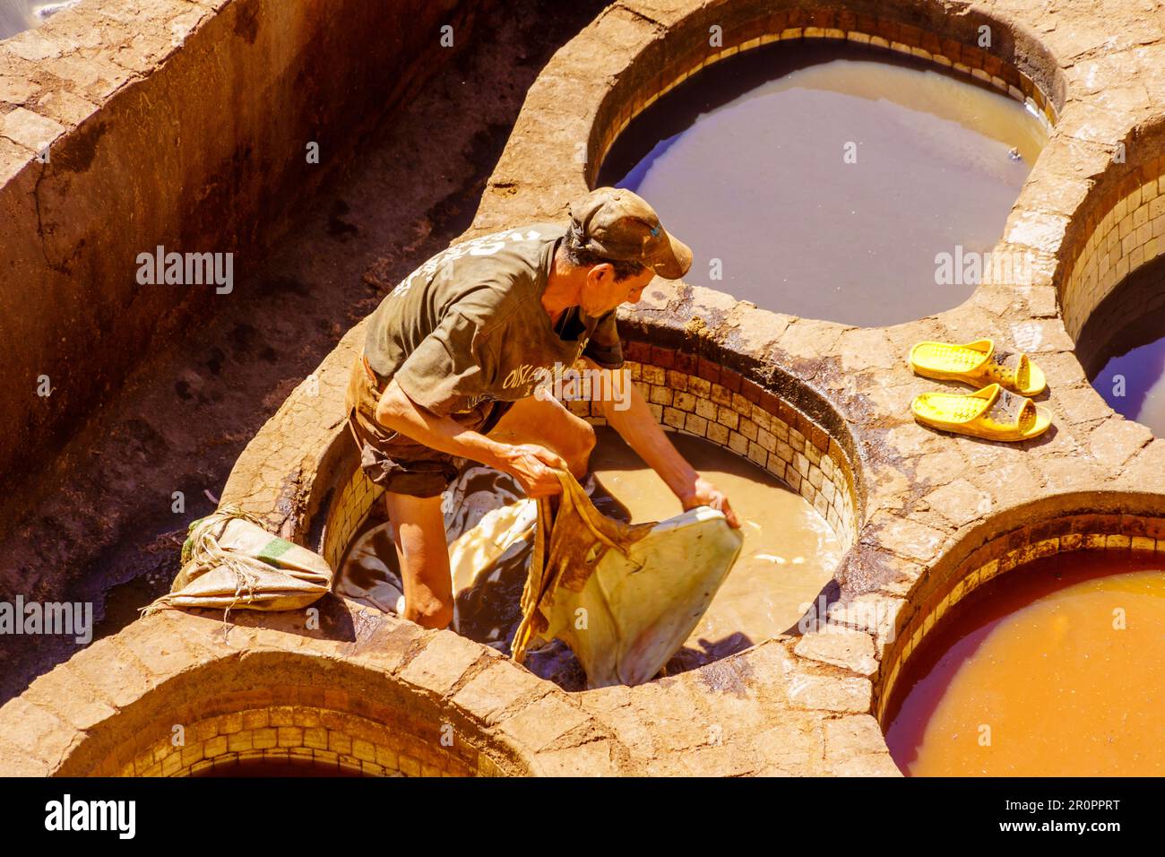 Fes, Morocco - March 31, 2023: Scene of the leather tannery, with workers and stone vats filled with various colors. Fes, Morocco Stock Photo