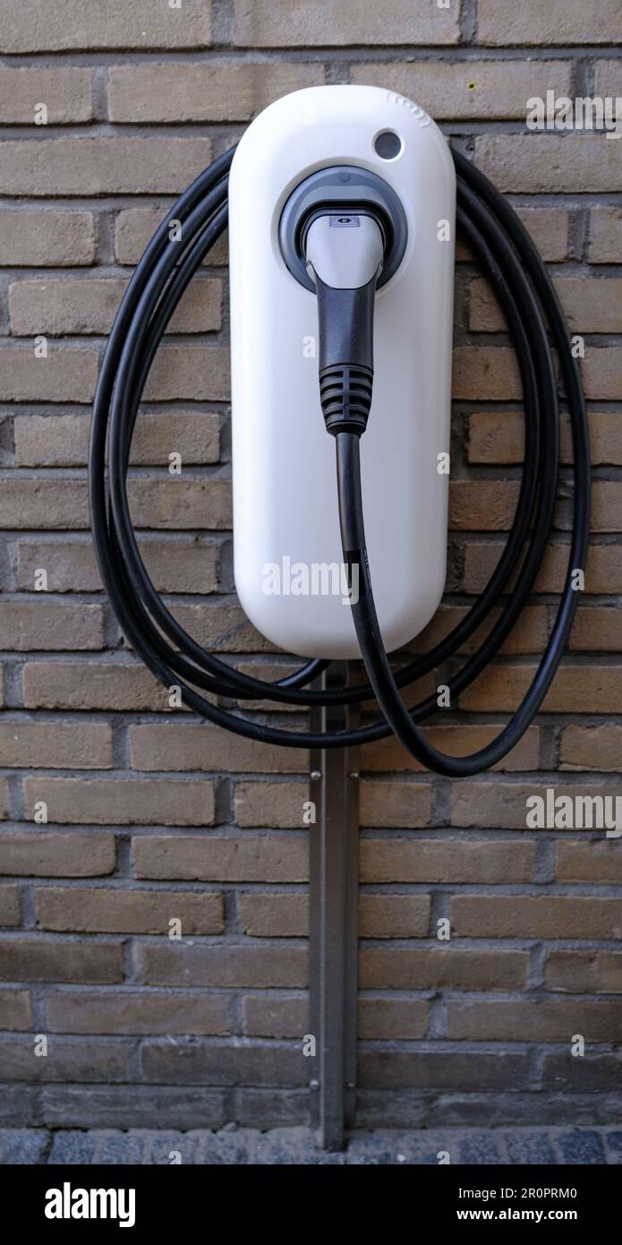 White electric car charger with cable attached installed at a house. Stock Photo