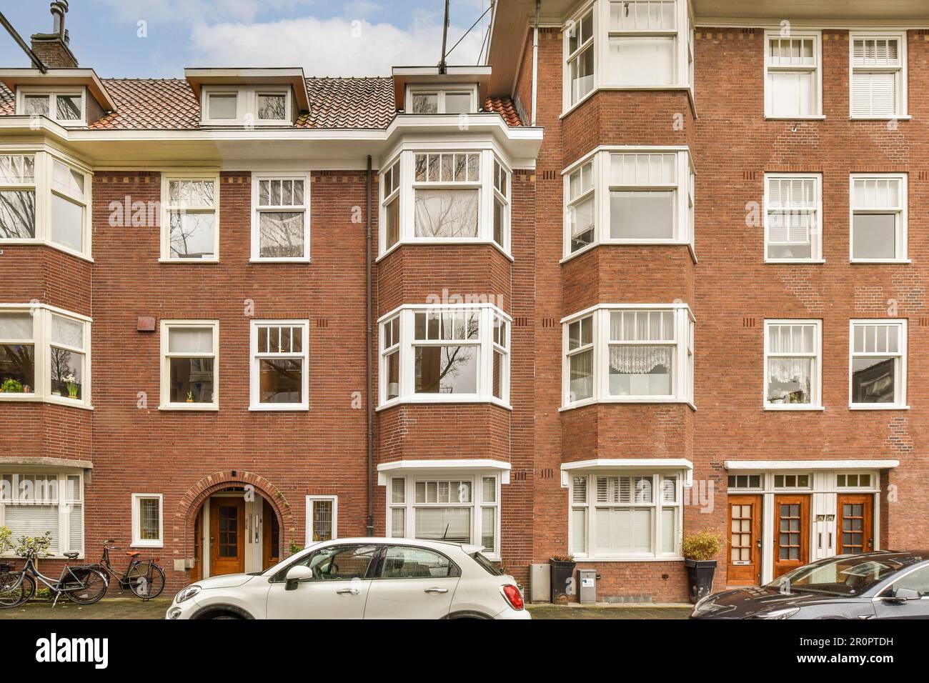 an apartment building with cars parked in the driveway and bicycles ...