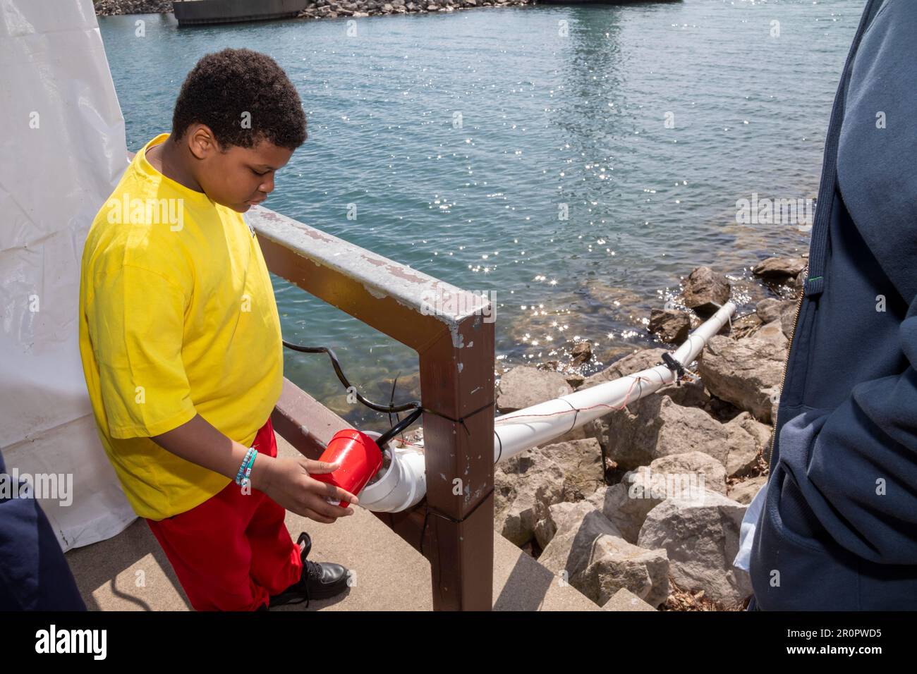Detroit, Michigan - Chilren helped stock salmon fry in the Detroit River by releasing them into a tube leading to the river at Milliken State Park. Stock Photo