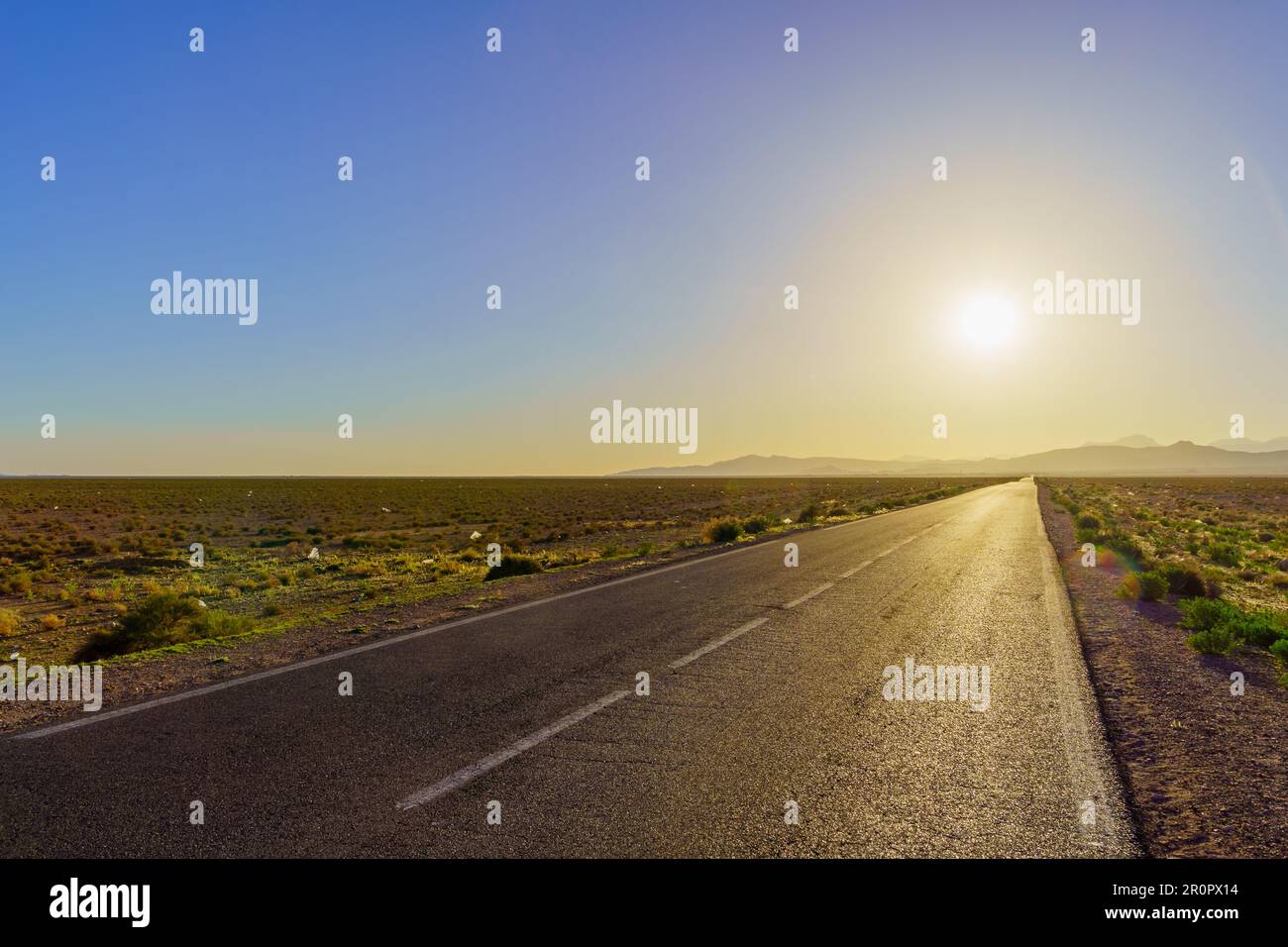 View of a desert road, with the Atlas Mountains in the background. Central Morocco Stock Photo