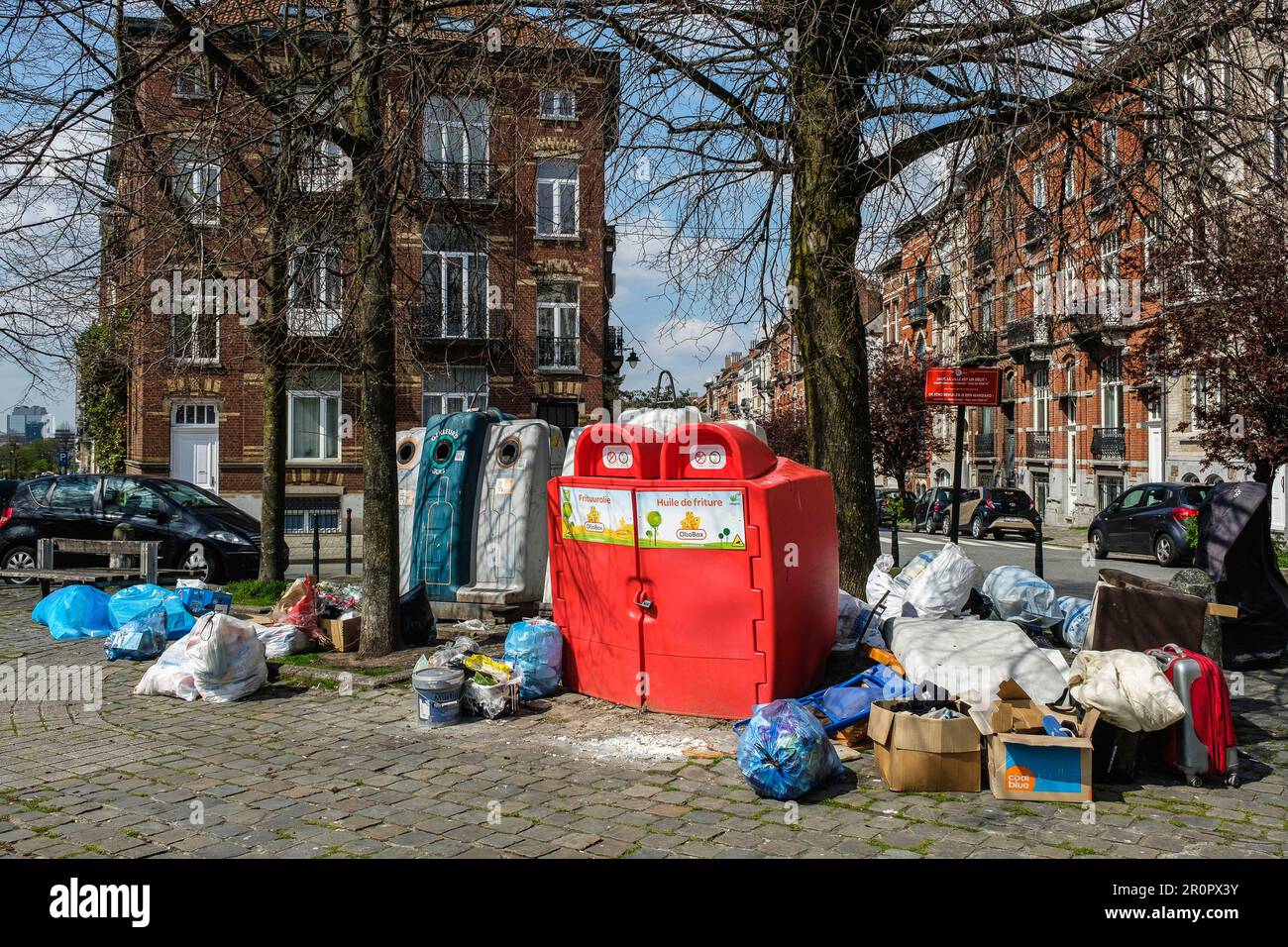 Unauthorized waste and trashes dump in the middle of a square and around the glass bootle bin and oil bin | Depôt clandestin de detritus, poubelles et Stock Photo