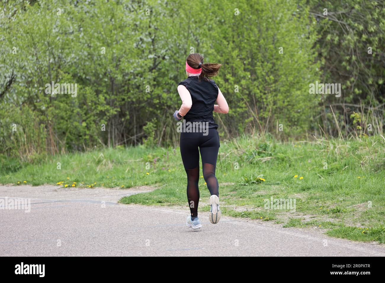 Girl running in spring park, rear view. Alone runner, concept of workout, slimming in green season Stock Photo