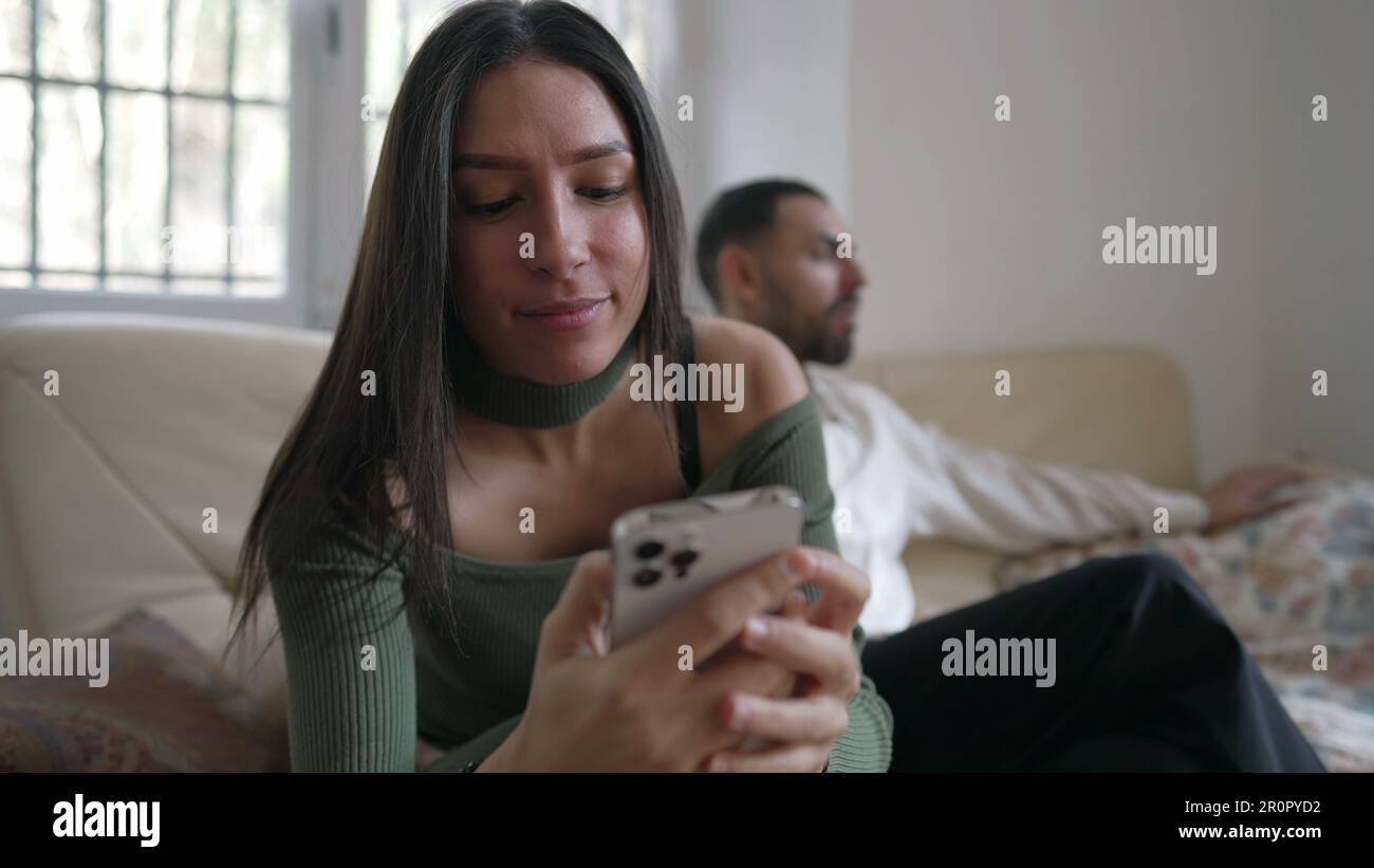 Young woman checking phone sitting at home couch with boyfriend in ...