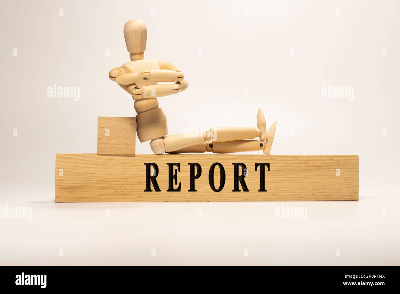 Report text written on wooden surface. wooden man. Stock Photo