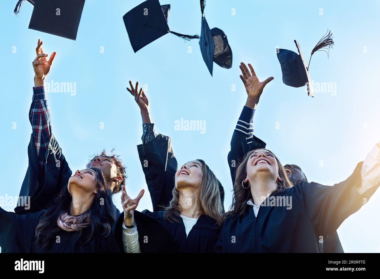 Victory is ours. a group of students throwing their hats in the air on ...