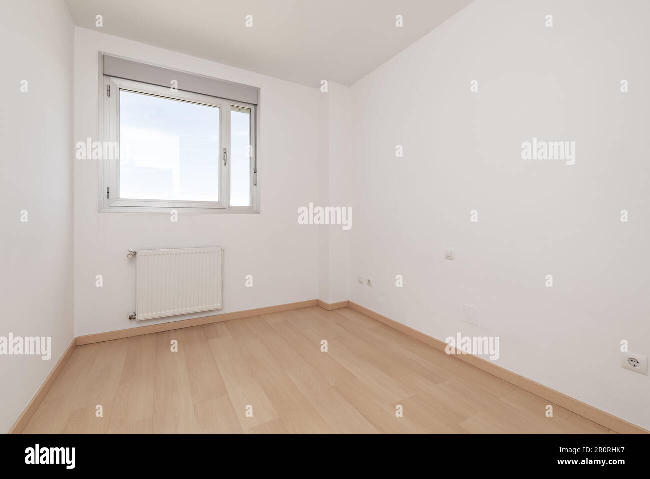 An empty room in an apartment with an aluminum and glass window with a radiator below Stock Photo