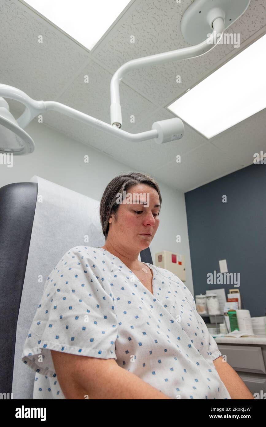 Low angle view of young 30s woman in dermatology clinic in medical gown