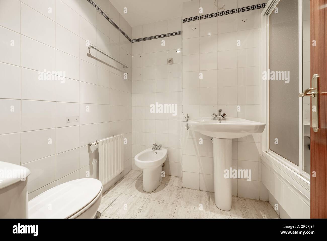 A full bathroom with showers with screens, white porcelain toilets and
