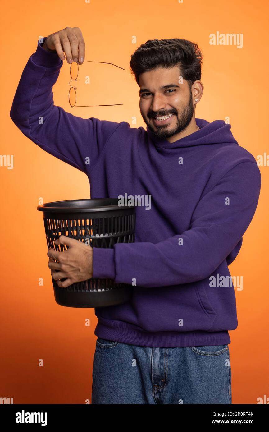 Indian bearded man taking off throwing out glasses into bin after
