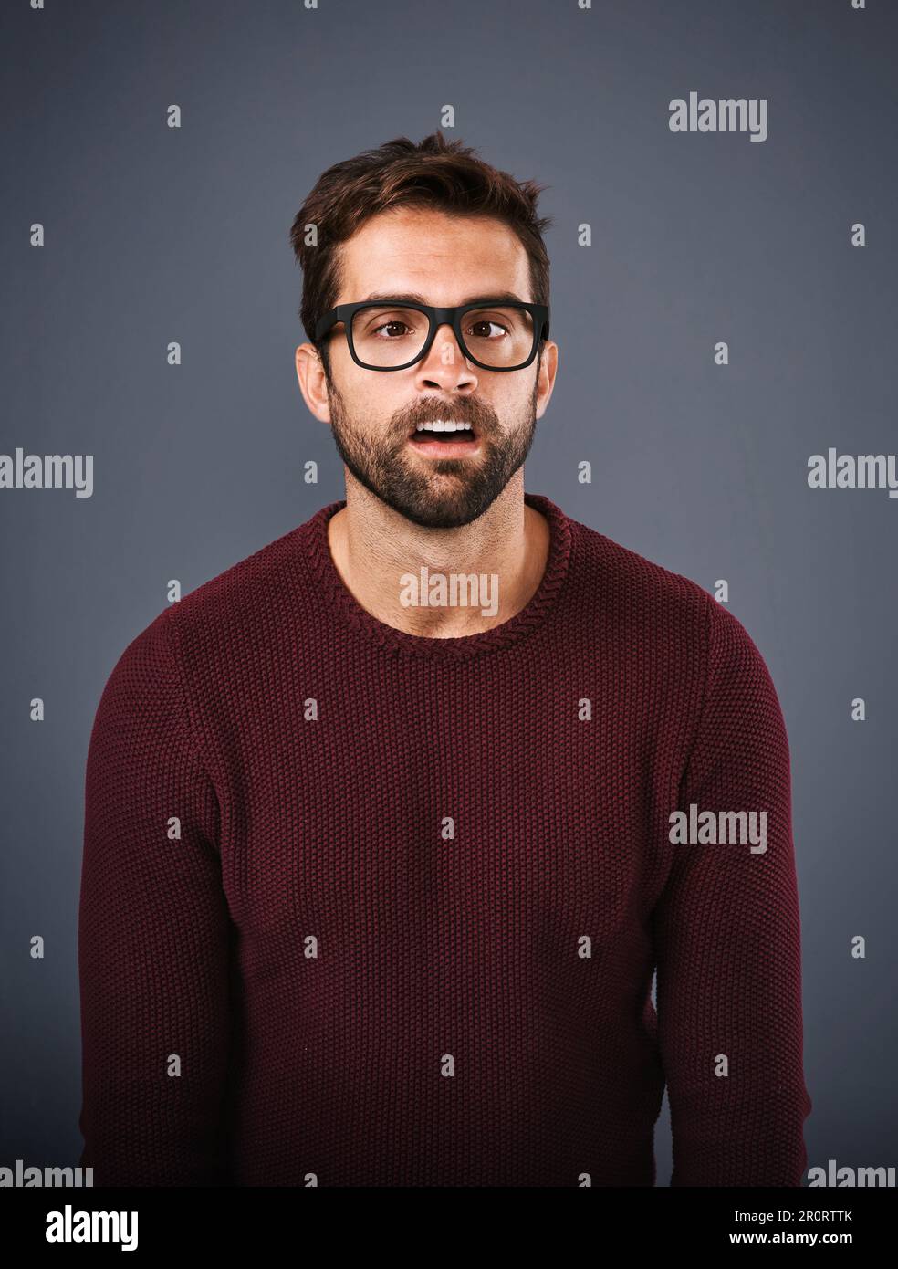 Messing around. Studio shot of a handsome young man pulling funny faces against a gray background. Stock Photo