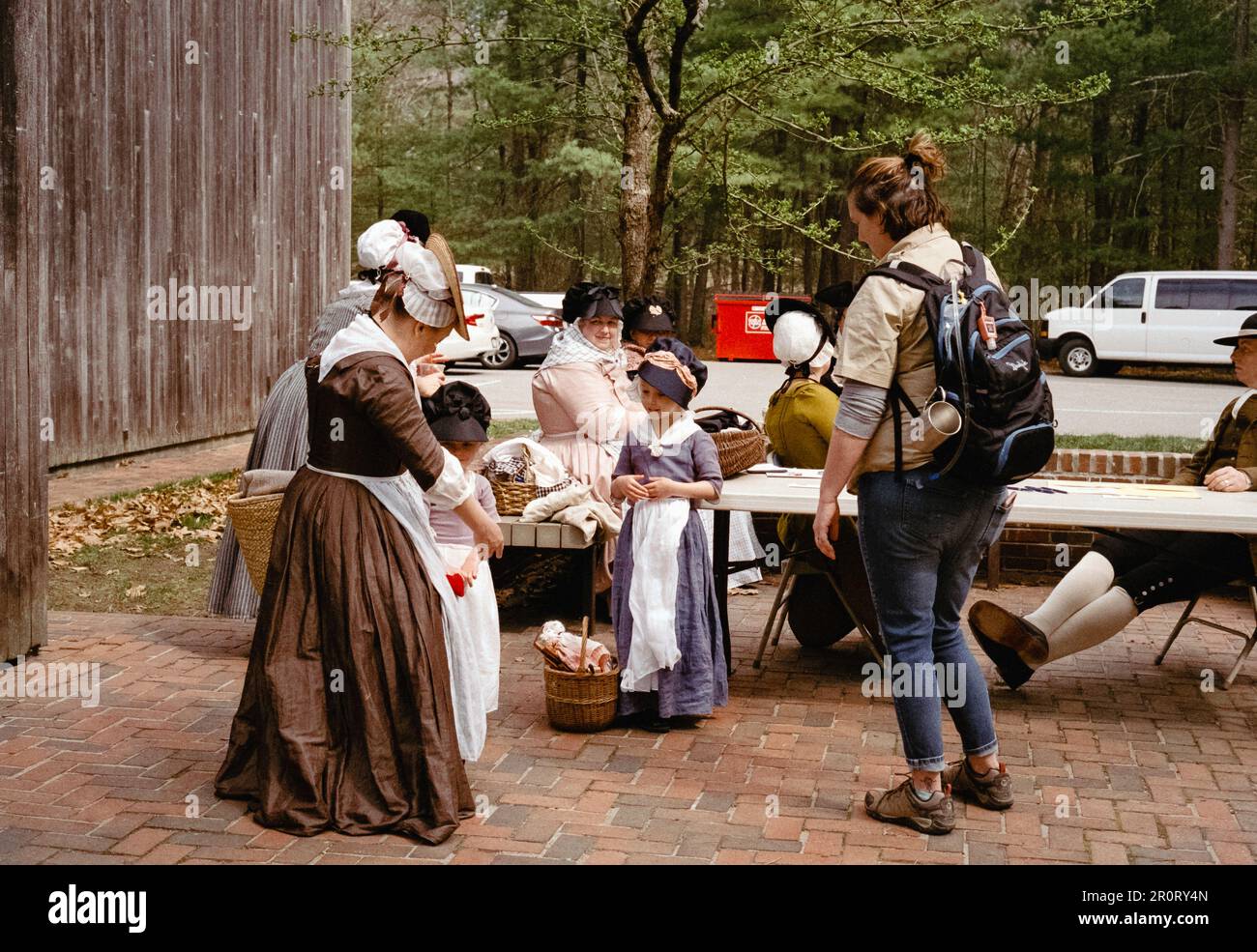 Lexington, Massachusetts USA - April 2023 - A visitor stops to chat with women and children dressed in Colonial period clothing behind the Minuteman N Stock Photo