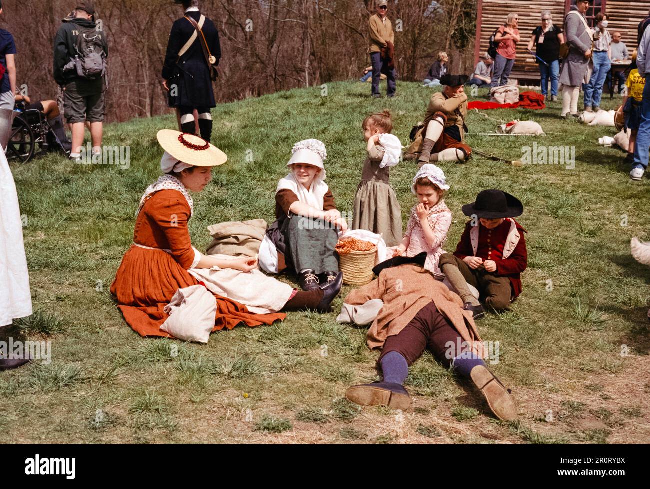 Lexington, Massachusetts USA - April 2023 - Women and children sit on the grass in front of the Captain William Smith house in the Minuteman National Stock Photo