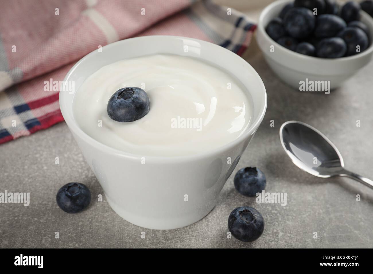 Bowl with delicious yogurt and blueberries on grey table, closeup Stock Photo