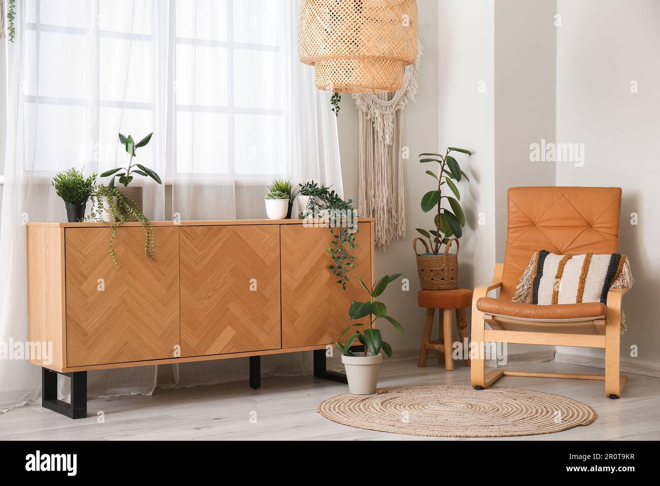 Interior of living room with wooden commode, houseplants and armchair ...