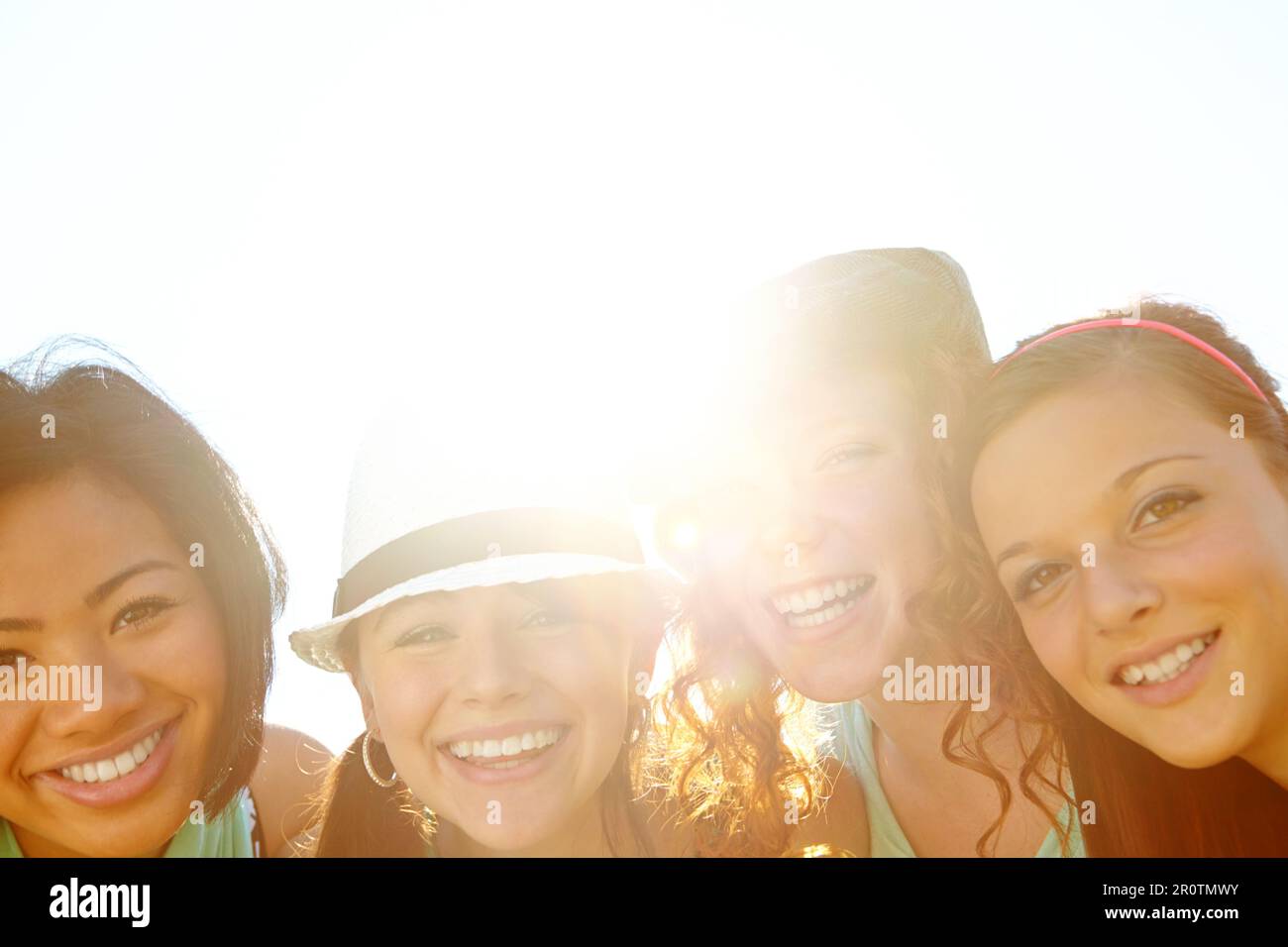 Enjoying a moment in the sun. Closeup shot of a group of teenage girls smiling with their arms around each others shoulders. Stock Photo
