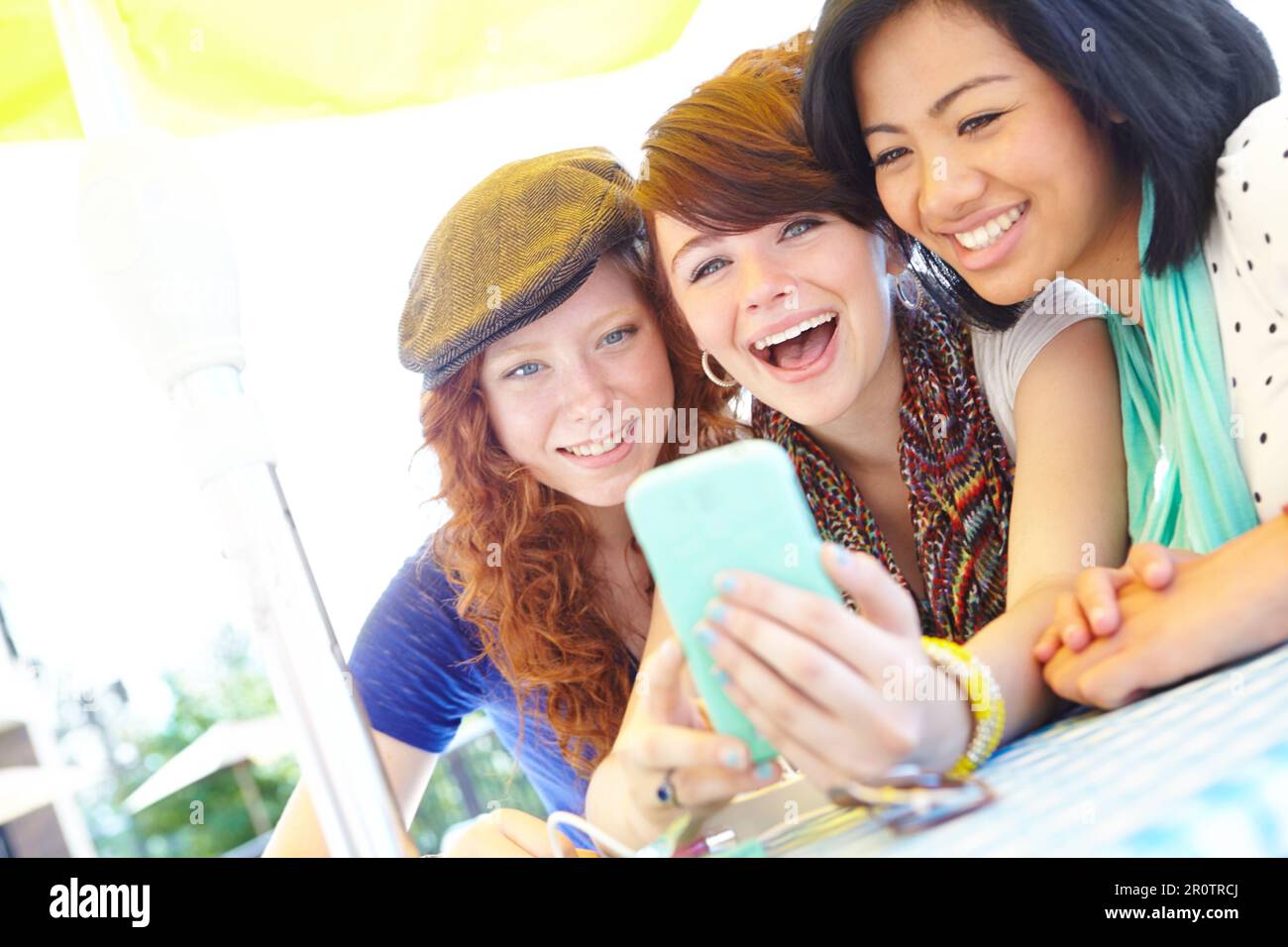 Technological fun. A group of adolescent girls laughing as they look at something on a smartphone screen. Stock Photo