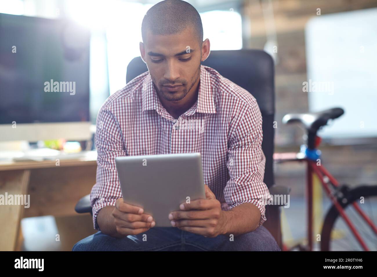 Focused on his online project. a designer using a digital tablet while working in an office. Stock Photo