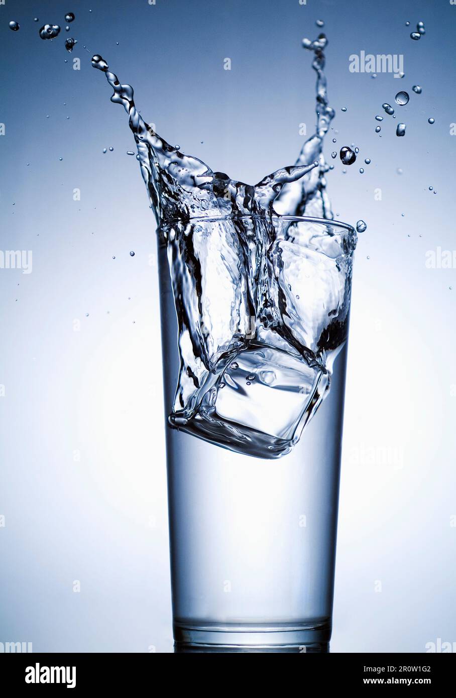 Ice cube falling into glass of water Stock Photo - Alamy