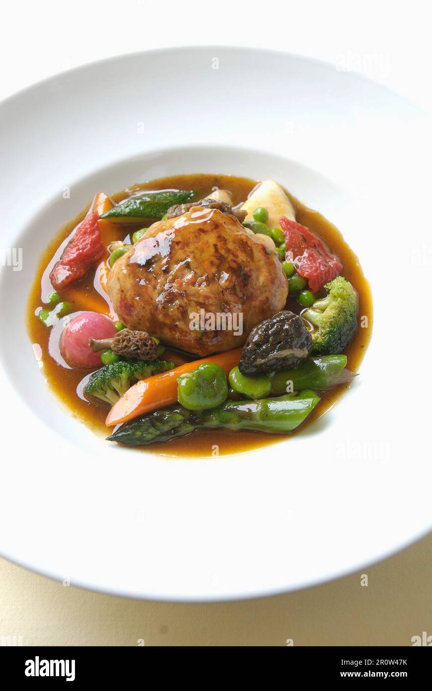 Stuffed veal Caillette with gravy and spring vegetables Stock Photo
