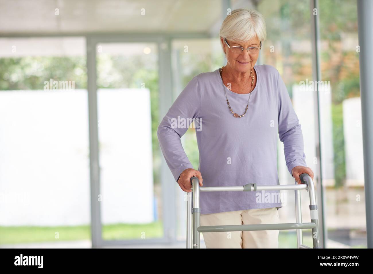 Post-surgery exercise is essential. a senior woman walking with care, using an orthopedic walker. Stock Photo