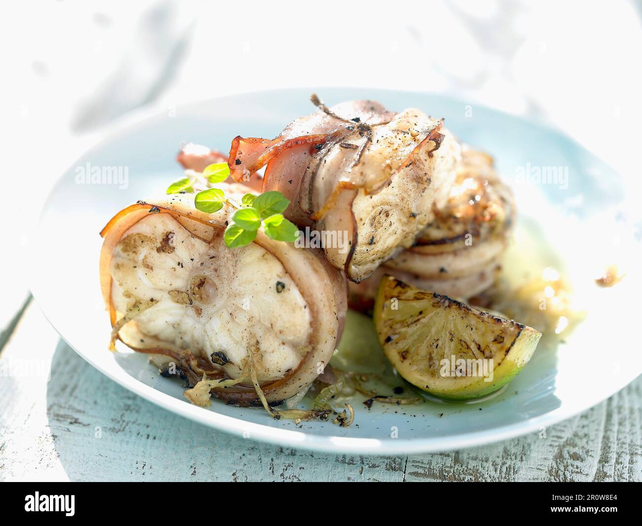 Monkfish wrapped in bacon with lemon Stock Photo