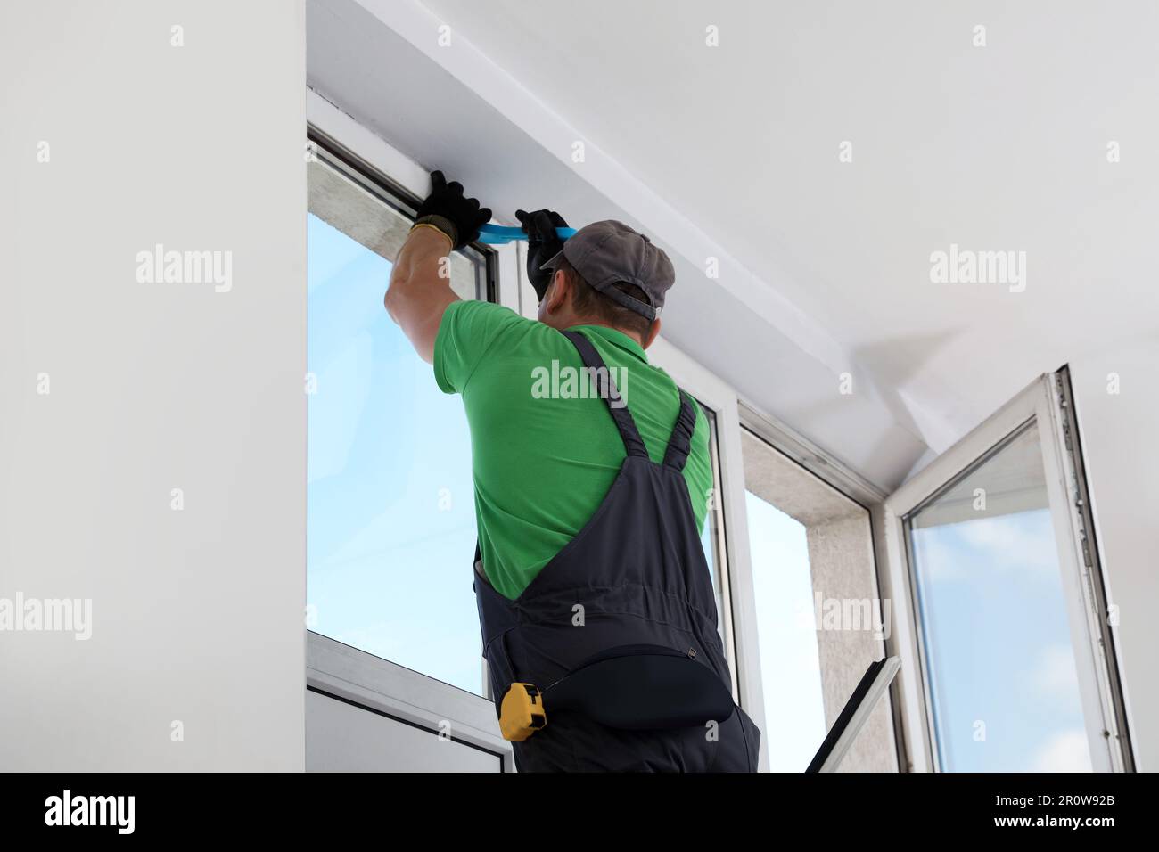 Worker in uniform installing window indoors, back view Stock Photo