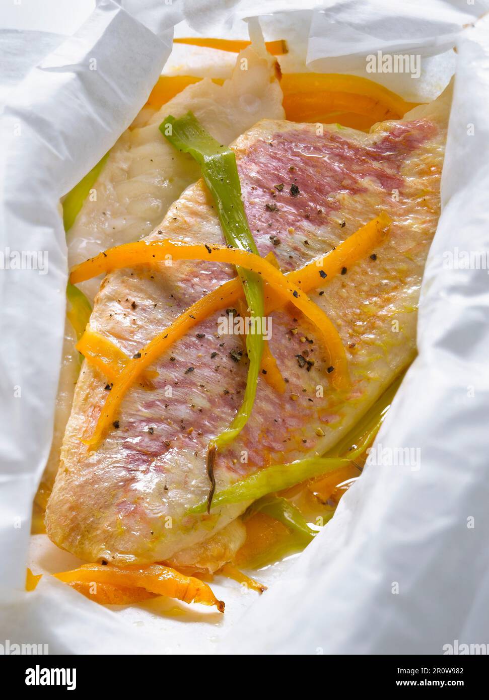 Red mullet with carrots and spring onions cooked in wax paper Stock