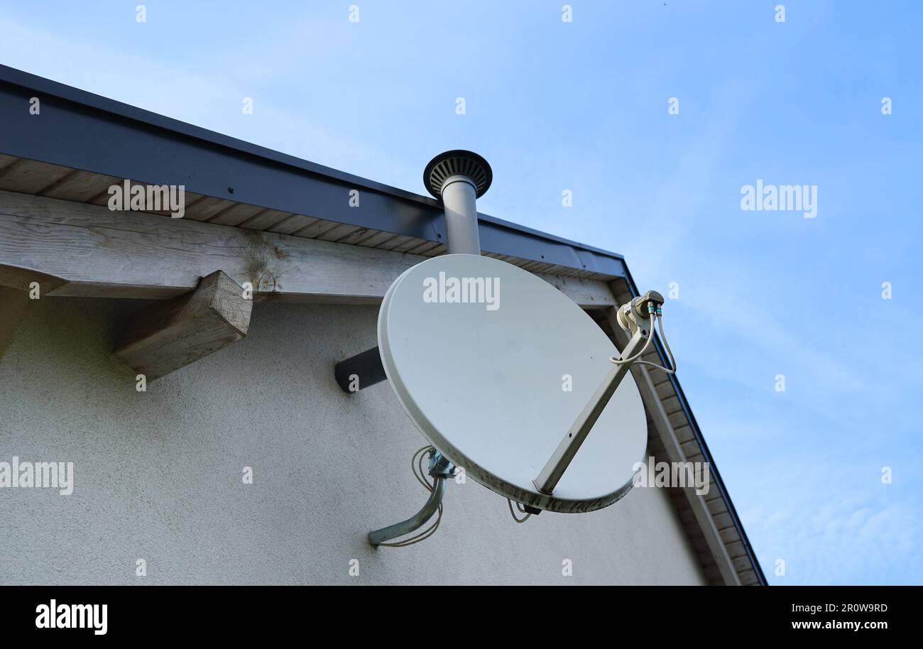 Satellite dish on the roof. Dish aerial installed to the wall. Receiving tv signals. Tv and internet connection aerial. Stock Photo