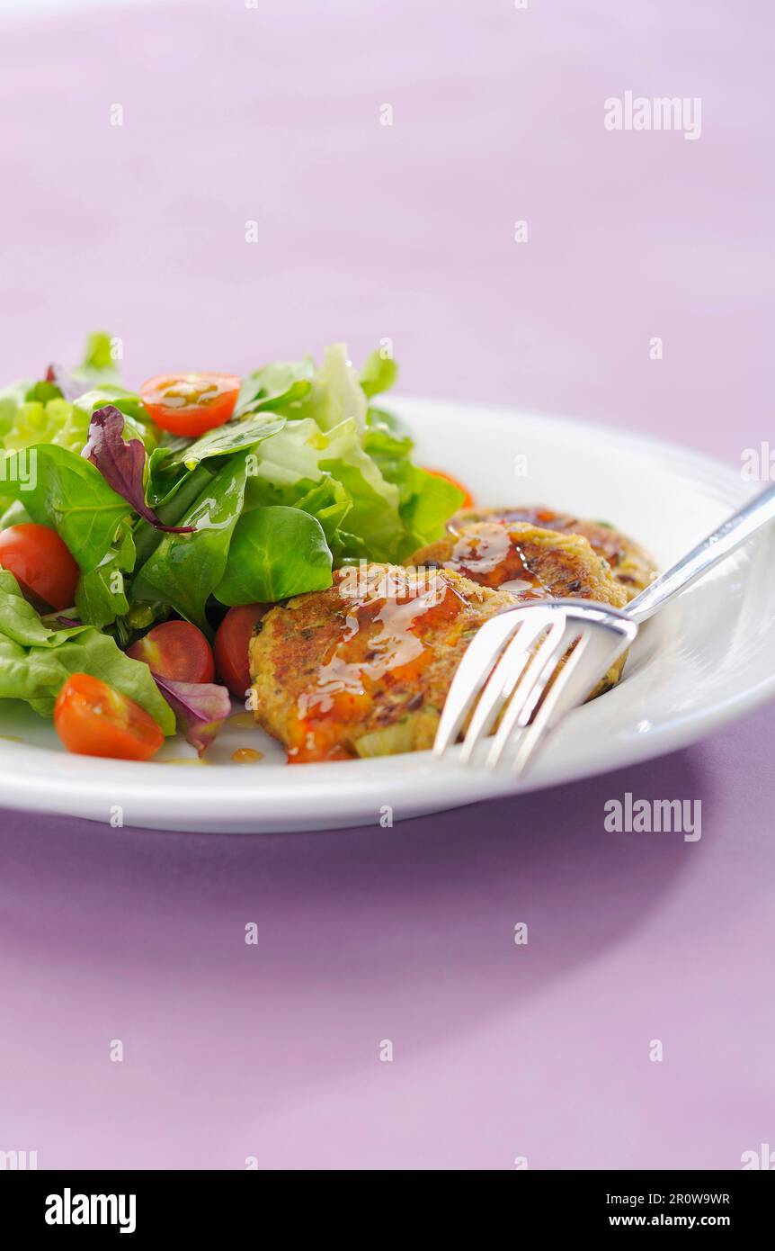 Small vegetable cakes with chili pepper sauce and mixed salad Stock Photo