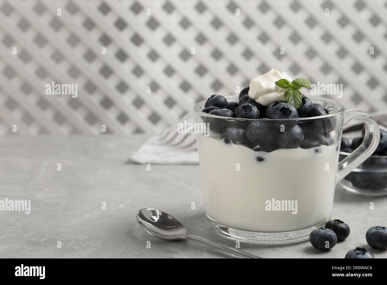 Delicious yogurt with blueberries served on grey marble table, space for text Stock Photo