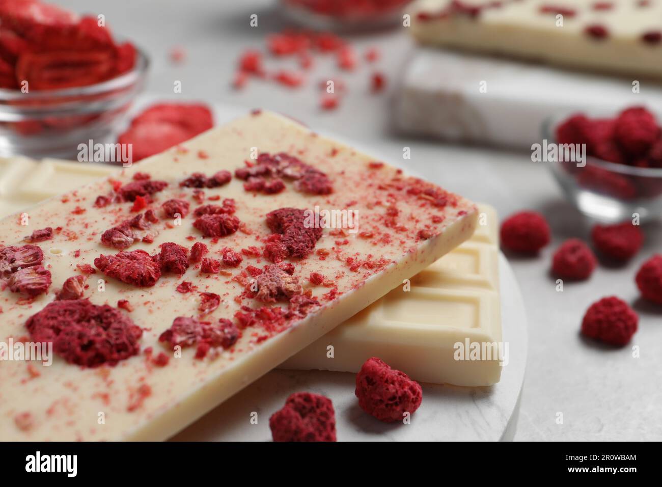 Chocolate bars with freeze dried raspberries on light marble table ...