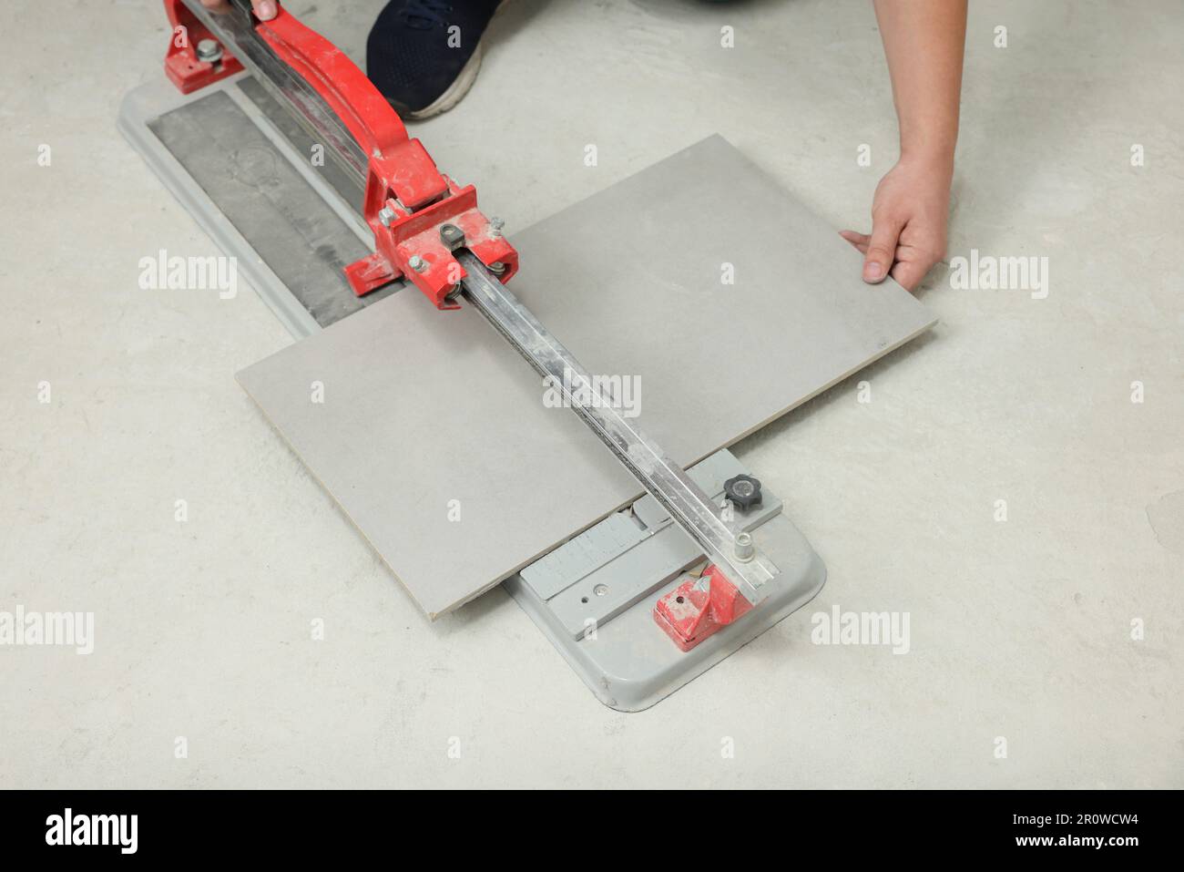 Worker using manual tile cutter on floor, closeup Stock Photo