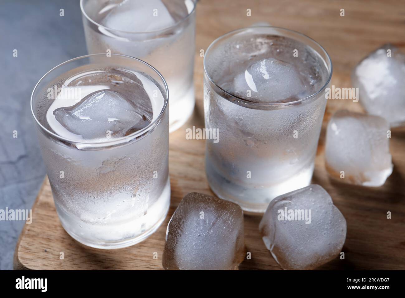 Shot glasses of vodka with ice cubes on table, closeup Stock Photo